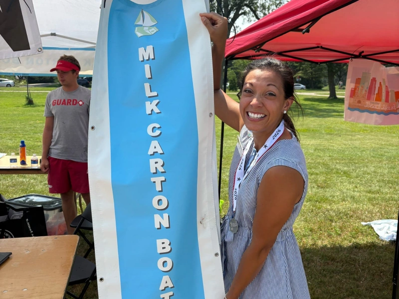 Volunteer holding Milk Carton Boat Races banner